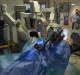 Un robot chirurgico da Vinci in funzione, con bracci meccanici illuminati che operano su un manichino in un ambiente ospedaliero.